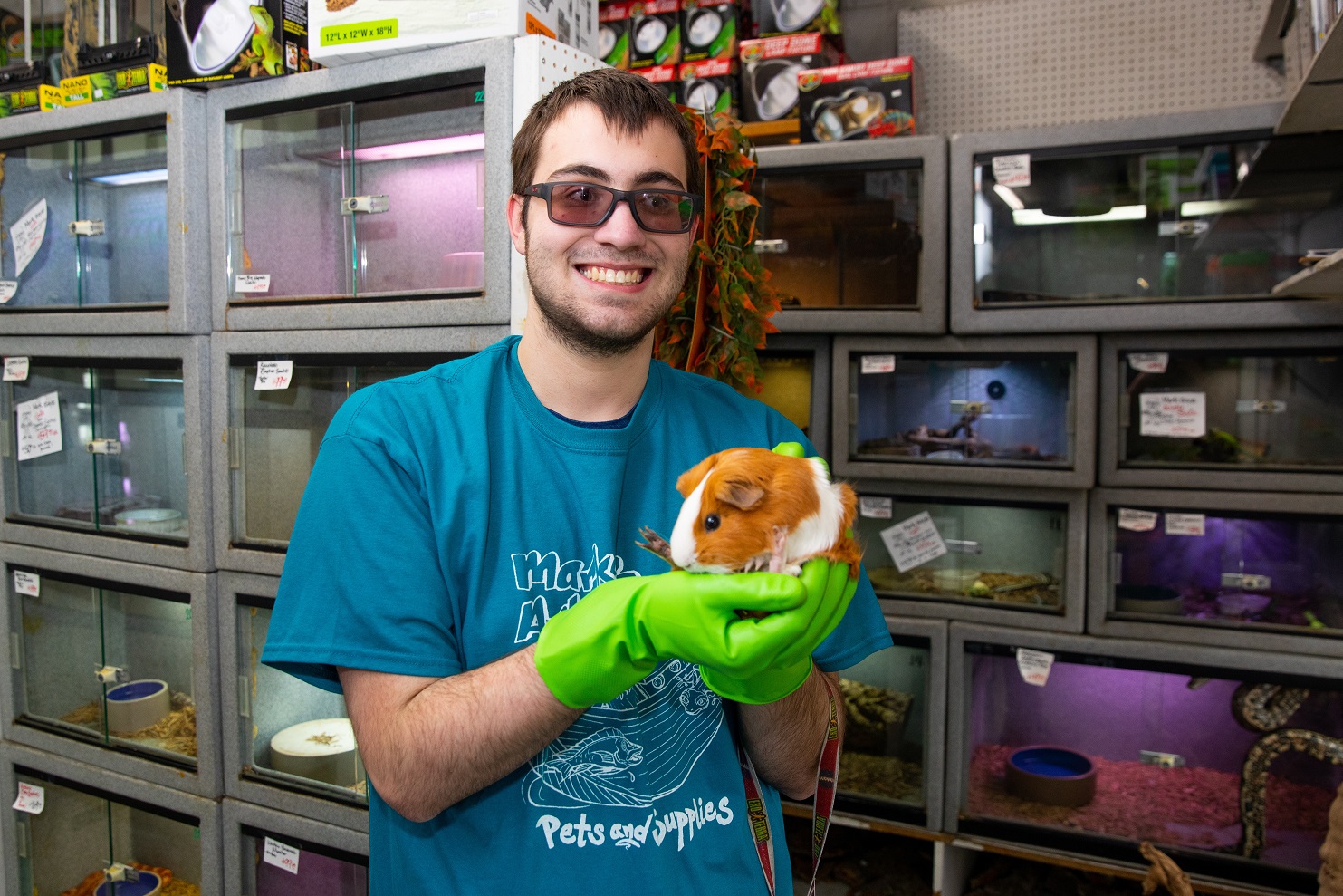 A man with a disability holding a guinea pig in an animal facility